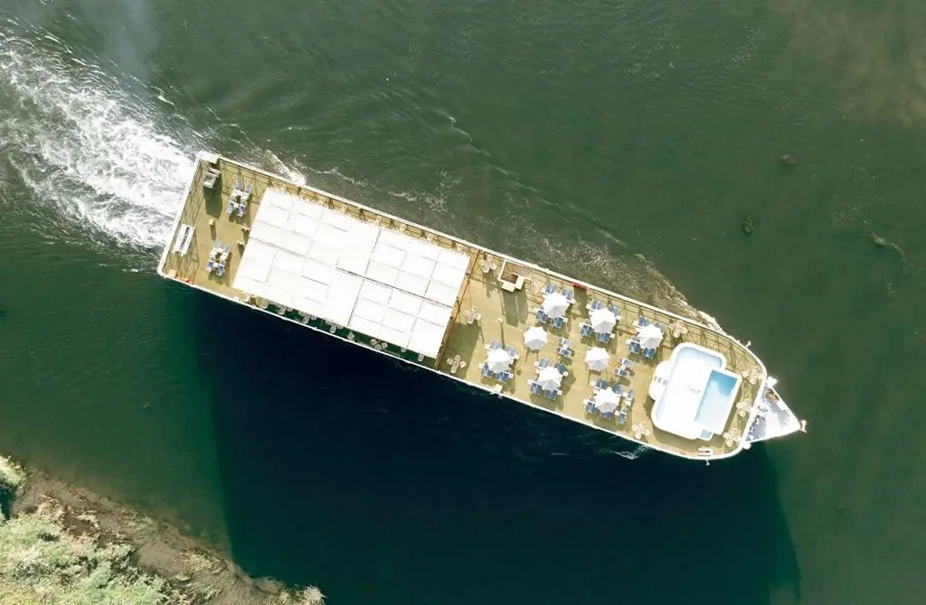 Aerial drone view of a vessel cruising the Nile, sun-deck pool and shaded gathering decks visible from above.